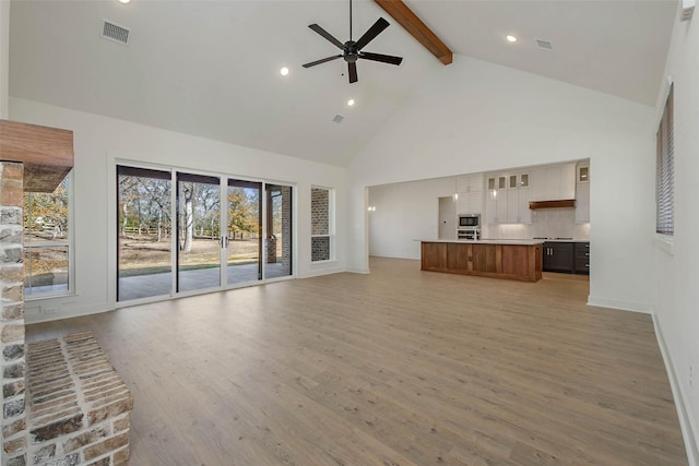 unfurnished living room featuring beam ceiling, light hardwood / wood-style flooring, high vaulted ceiling, and ceiling fan