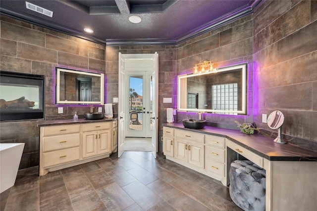 bathroom featuring tile walls, a bathing tub, a textured ceiling, and vanity