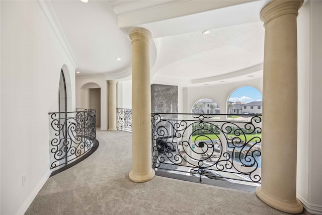 hall with crown molding, decorative columns, and carpet floors