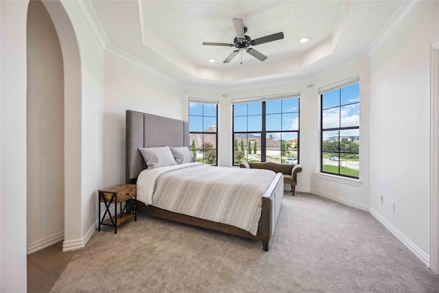 bedroom featuring a tray ceiling, a textured ceiling, light colored carpet, and ceiling fan