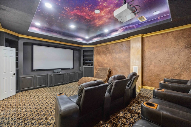 carpeted home theater room with built in shelves and a tray ceiling