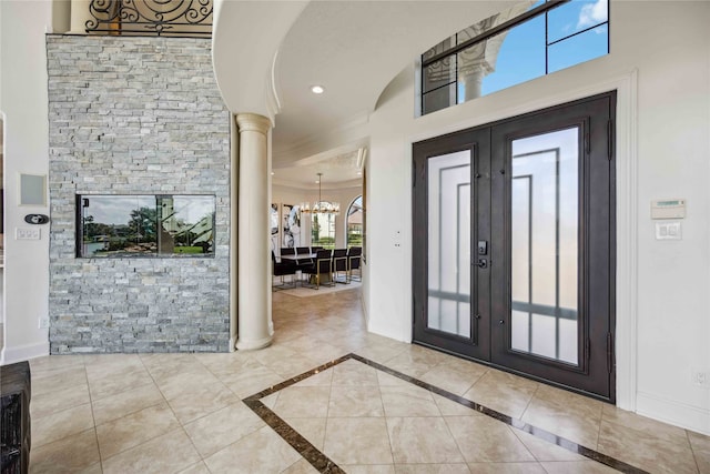 foyer entrance featuring a chandelier, french doors, and ornate columns