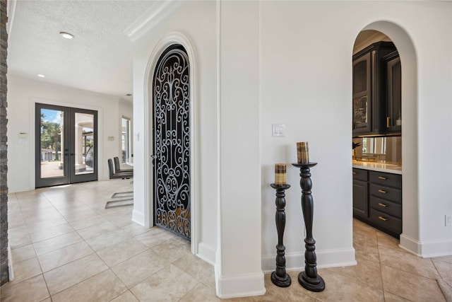 hall featuring ornamental molding, french doors, a textured ceiling, and light tile patterned flooring