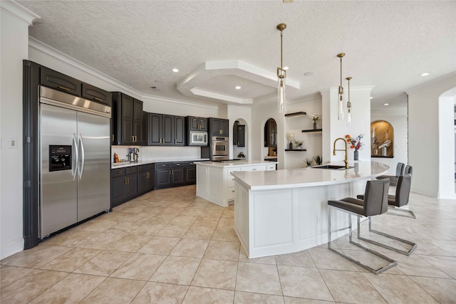 kitchen featuring hanging light fixtures, a textured ceiling, sink, built in appliances, and ornamental molding