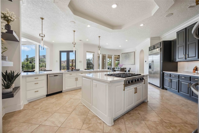 kitchen featuring hanging light fixtures, light tile patterned floors, appliances with stainless steel finishes, and a tray ceiling