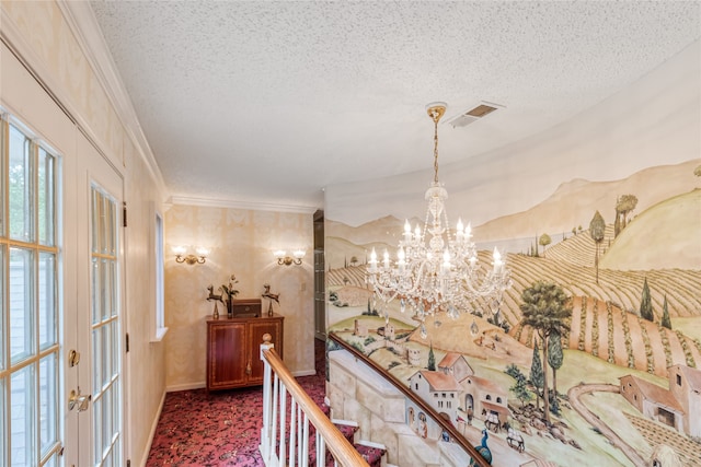 corridor with a textured ceiling, crown molding, french doors, and a chandelier