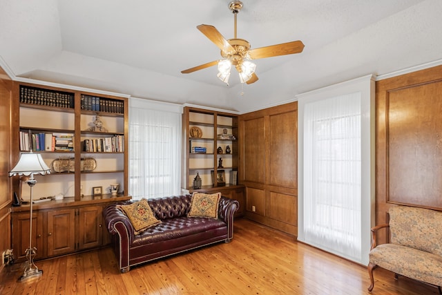 sitting room with light wood-type flooring, a raised ceiling, plenty of natural light, and ceiling fan