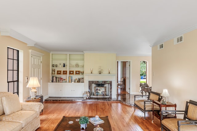 living room featuring crown molding, a premium fireplace, and wood-type flooring