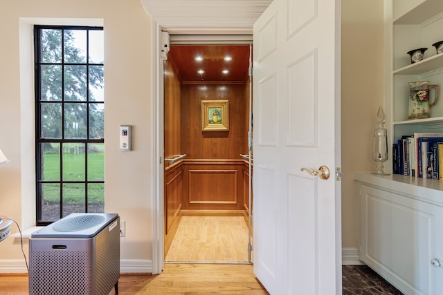 hallway featuring a healthy amount of sunlight, elevator, and hardwood / wood-style flooring