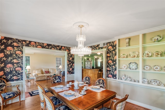 dining room featuring crown molding, a chandelier, and hardwood / wood-style flooring