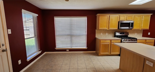 kitchen featuring appliances with stainless steel finishes, tasteful backsplash, a wealth of natural light, and light tile patterned flooring