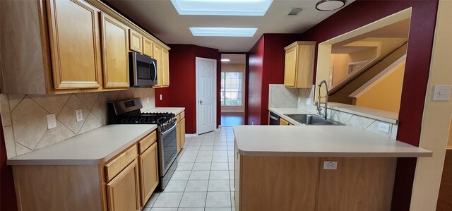 kitchen with light tile patterned floors, kitchen peninsula, sink, decorative backsplash, and appliances with stainless steel finishes