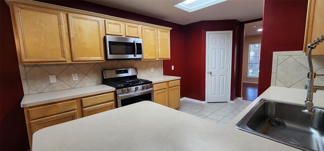 kitchen with light tile patterned floors, stainless steel appliances, and decorative backsplash