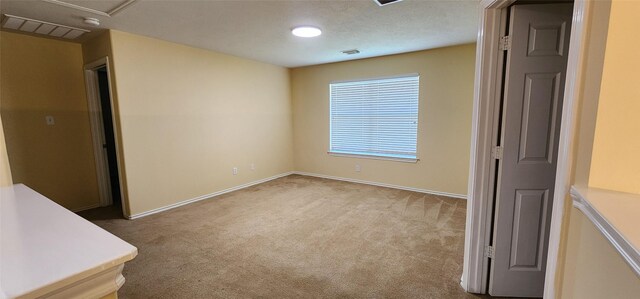 unfurnished room featuring a textured ceiling and light colored carpet