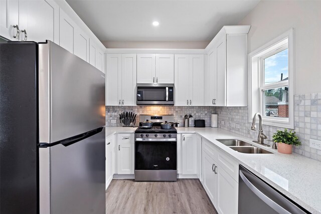 kitchen featuring decorative backsplash, white cabinets, appliances with stainless steel finishes, and sink