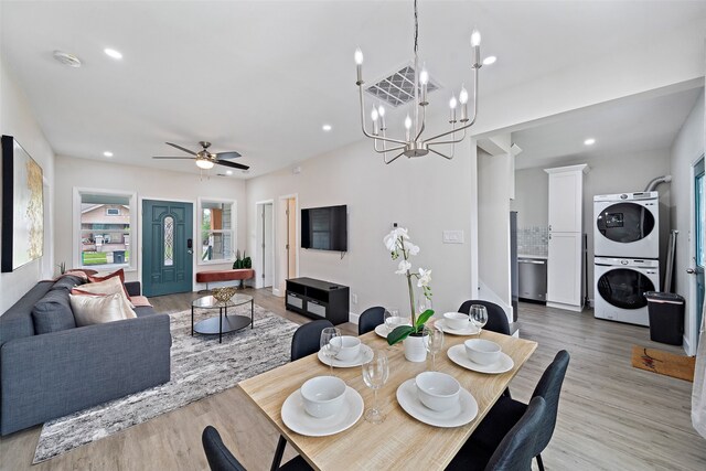 dining area with ceiling fan with notable chandelier, stacked washer and dryer, and light hardwood / wood-style flooring