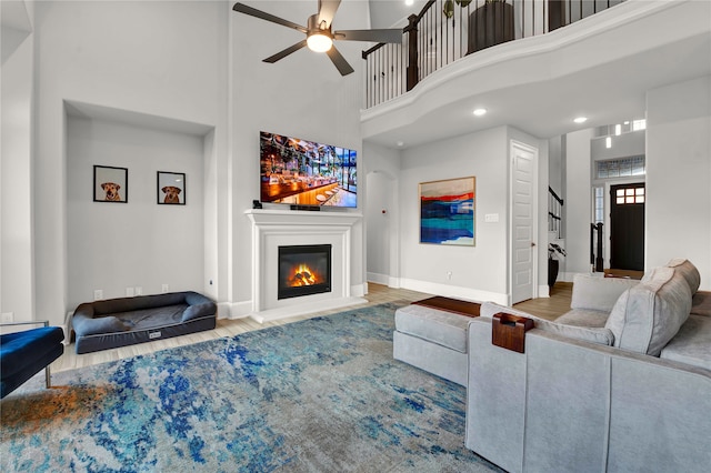 living room featuring ceiling fan, hardwood / wood-style flooring, and a high ceiling