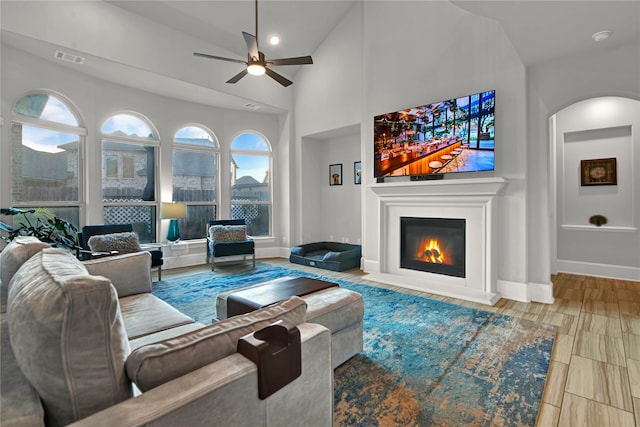 living room with high vaulted ceiling, ceiling fan, light hardwood / wood-style flooring, and a healthy amount of sunlight