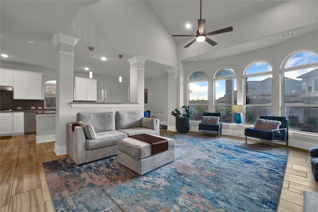 living room featuring ceiling fan, light hardwood / wood-style floors, ornate columns, and high vaulted ceiling