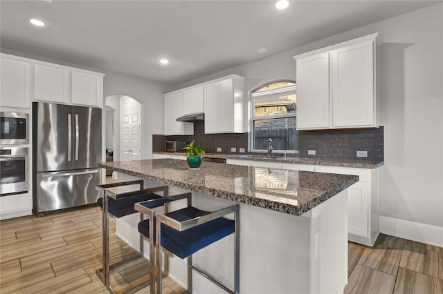 kitchen with white cabinets, appliances with stainless steel finishes, tasteful backsplash, and a kitchen island