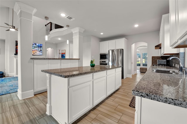 kitchen featuring hanging light fixtures, white cabinetry, a kitchen island, stainless steel appliances, and ceiling fan