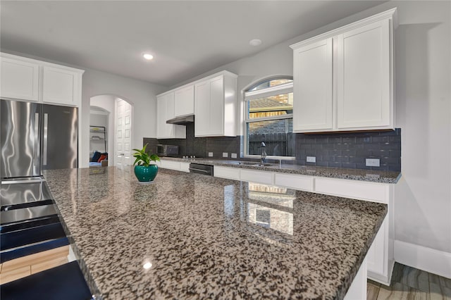 kitchen featuring dark stone counters, white cabinetry, a center island, and hardwood / wood-style flooring