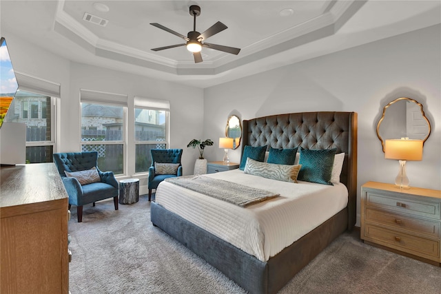 bedroom featuring carpet floors, ornamental molding, a tray ceiling, and ceiling fan