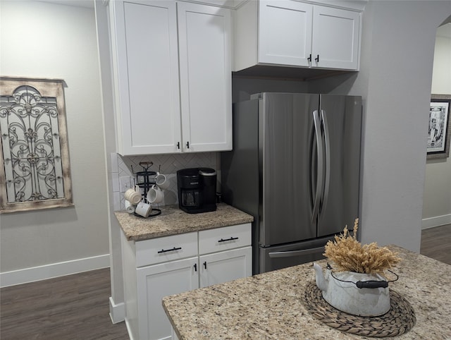 kitchen with light stone counters, stainless steel fridge, and white cabinets