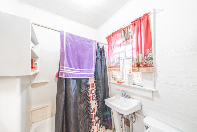 full bathroom with wood walls, crown molding, toilet, sink, and shower / bath combo