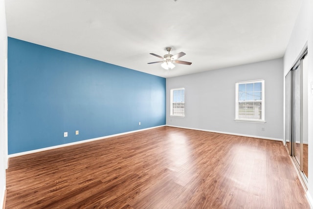 unfurnished bedroom featuring baseboards, wood finished floors, a ceiling fan, and a closet