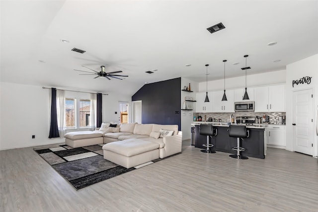 living room with light wood-type flooring, ceiling fan, and lofted ceiling