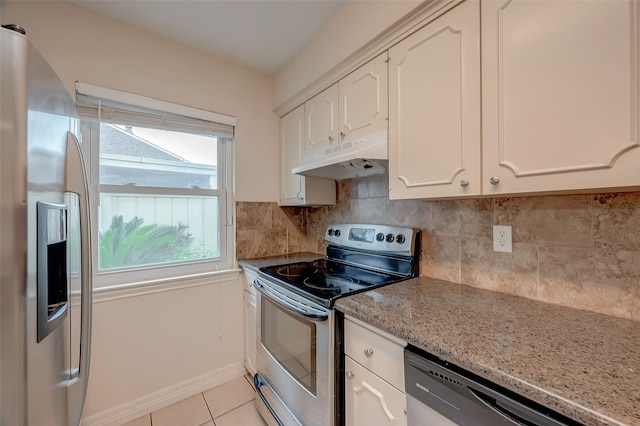 kitchen featuring appliances with stainless steel finishes, decorative backsplash, light tile patterned flooring, white cabinetry, and light stone counters