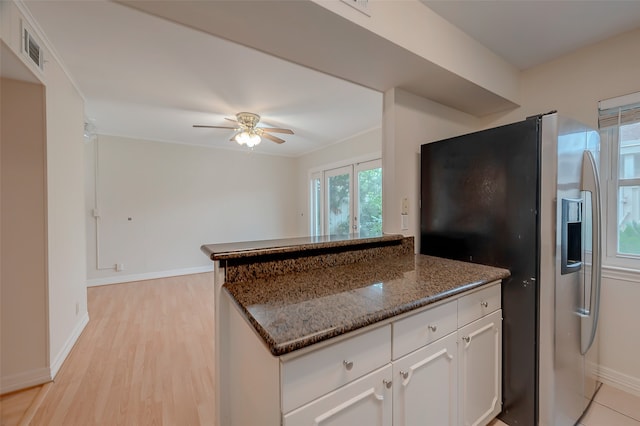 kitchen featuring stainless steel fridge, light hardwood / wood-style floors, dark stone countertops, white cabinetry, and ceiling fan