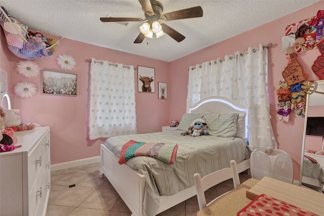 bedroom featuring ceiling fan, light tile patterned floors, and a textured ceiling