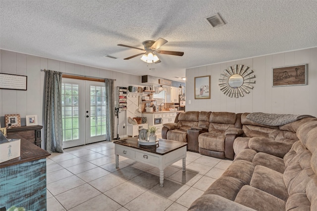 living room with french doors, a textured ceiling, light tile patterned flooring, and ceiling fan