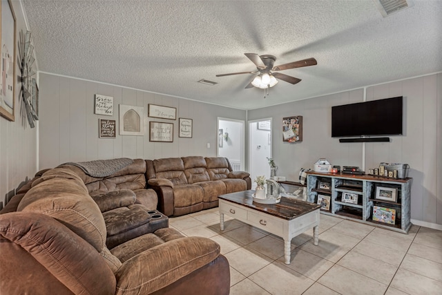 living room with a textured ceiling, light tile patterned floors, and ceiling fan