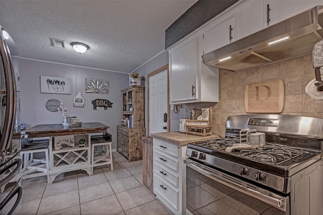 kitchen with white cabinets, appliances with stainless steel finishes, light tile patterned floors, and a textured ceiling