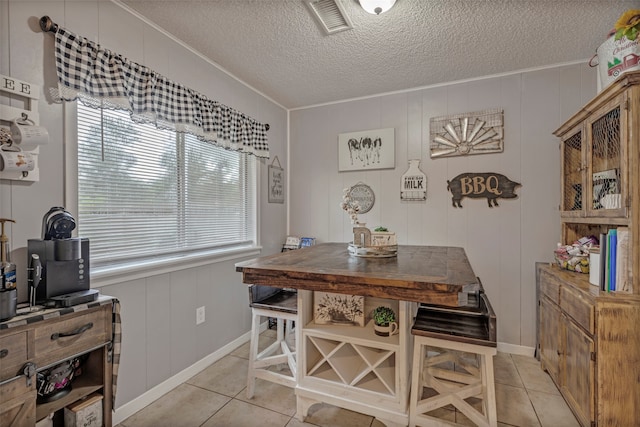 tiled dining room with wood walls, a textured ceiling, and a healthy amount of sunlight