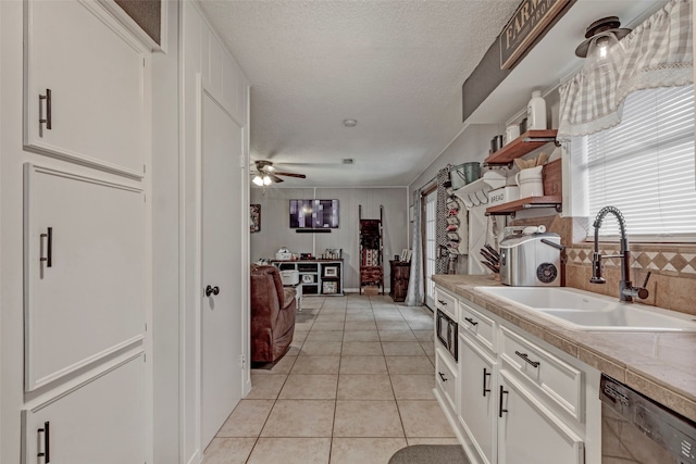 kitchen with tile counters, ceiling fan, dishwashing machine, and white cabinetry