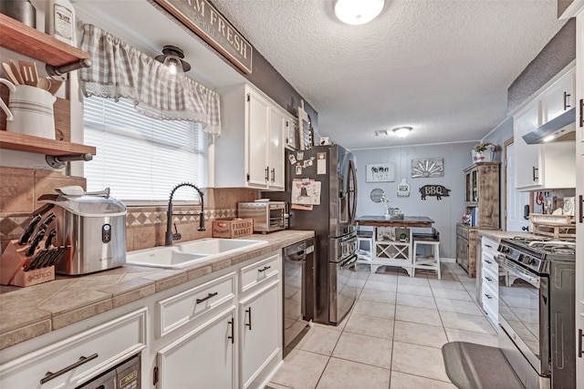 kitchen featuring tile counters, stainless steel appliances, white cabinetry, and sink