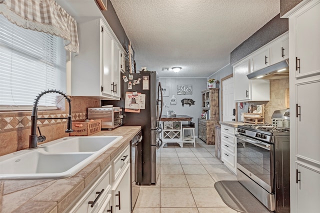 kitchen featuring appliances with stainless steel finishes, tile counters, sink, and white cabinets