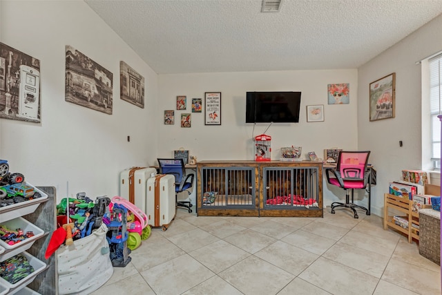 recreation room featuring a textured ceiling and light tile patterned floors