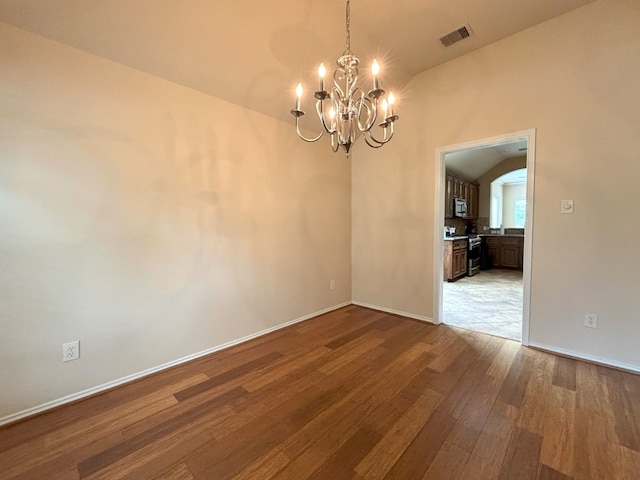 unfurnished room featuring lofted ceiling, wood-type flooring, and a notable chandelier