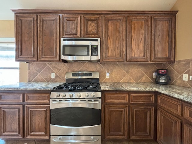 kitchen featuring appliances with stainless steel finishes, light stone countertops, and decorative backsplash