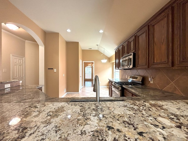 kitchen featuring appliances with stainless steel finishes, crown molding, sink, decorative backsplash, and lofted ceiling