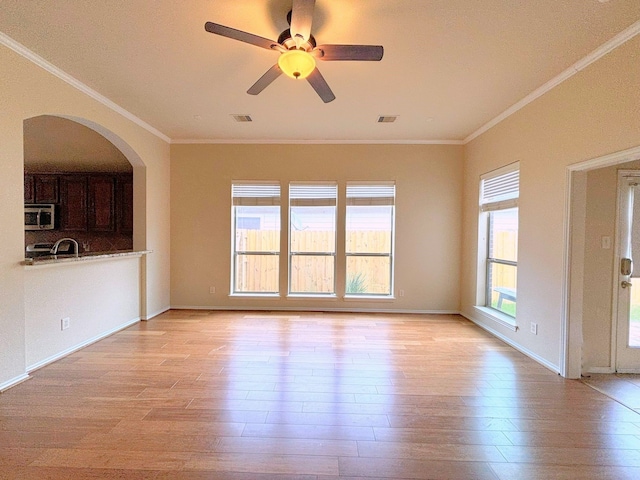 unfurnished living room featuring sink, ceiling fan, light hardwood / wood-style floors, and ornamental molding