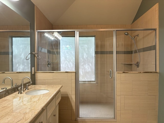 bathroom with vanity, lofted ceiling, plenty of natural light, and a shower with door