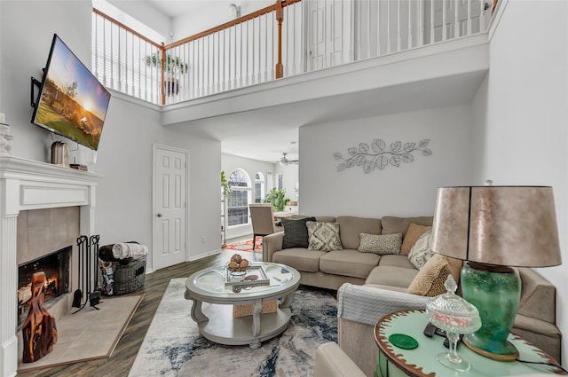 living room featuring hardwood / wood-style floors, ceiling fan, a fireplace, and a high ceiling