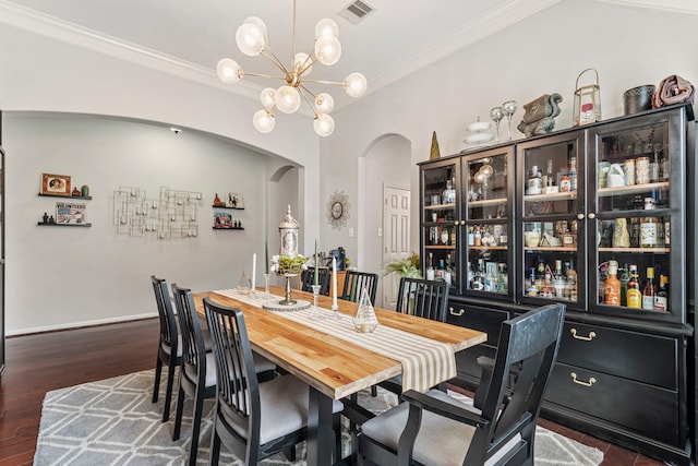 dining room featuring visible vents, crown molding, dark wood-style floors, an inviting chandelier, and arched walkways