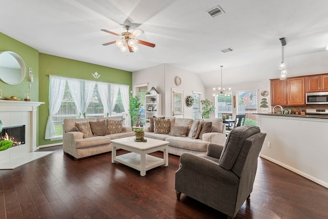 living area featuring visible vents, a healthy amount of sunlight, a fireplace, and dark wood-style flooring